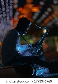 A Young African-American Man With A Saxaphone In A Night City Street