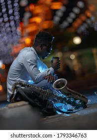 A Young African-American Man With A Saxaphone In A Night City Street