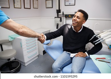 Young African-American Man Shaking Hand Of Crop Dentist Having Visit In Medical Clinic. 