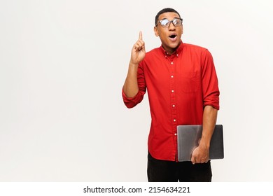 Young African-American short-cutted student in glasses holds laptop and finger point up isolated on white background, guy in red shirt excited with breakthrough. Tech geek come with task solution