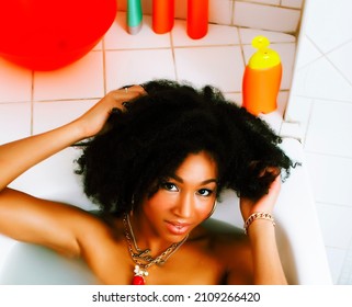 young african-american teen girl laying in bath with foam, wearing swag jewelry flawless, making selfie