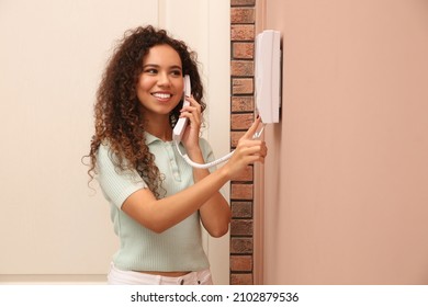 Young African-American woman answering intercom call indoors