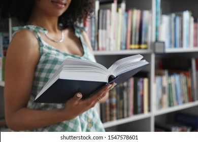 Young African-American woman with book in library, closeup