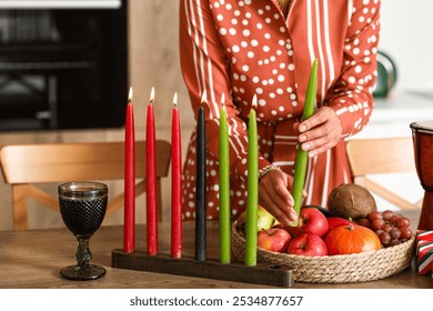 Young African-American woman with candles celebrating Kwanzaa in kitchen, closeup - Powered by Shutterstock