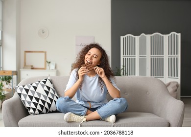 Young African-American woman eating chocolate at home - Powered by Shutterstock