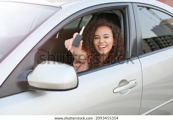 Young
African-American woman with key sitting in new
car