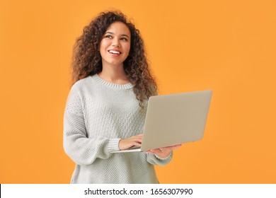 Young African-American Woman With Laptop On Color Background