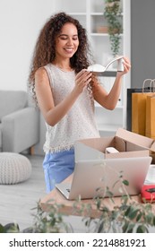 Young African-American Woman With New Shoes At Home. Online Shopping