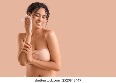 Young African-American woman removing makeup with wipe on beige background - Powered by Shutterstock