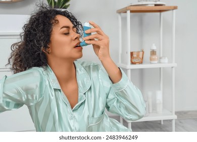 Young African-American woman using asthma inhaler in bathroom - Powered by Shutterstock