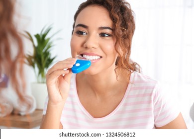 Young African-American Woman Using Teeth Whitening Device At Home