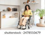 Young African-American woman in wheelchair at home