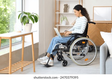 Young African-American woman in wheelchair with laptop at home - Powered by Shutterstock