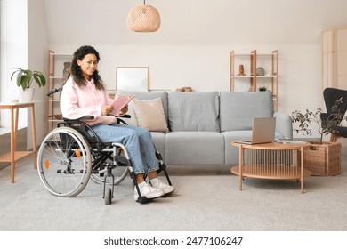 Young African-American woman in wheelchair reading book at home - Powered by Shutterstock