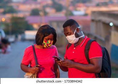 Young Africans wearing locally made and surgical face mask for protection during covid-19 pandemic - Black millennials using phone - Africans in relationship communicating on phone in school or campus - Powered by Shutterstock