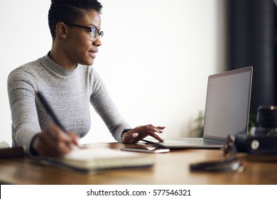 Young Afro American Female Executive  Filling In Application On Official Site Of Media Marketing Corporation Ordering Services And Collaboration Via Laptop Computer And Wireless Internet Indoor