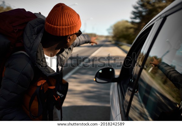 Young afro american guy stopped auto to ask to\
drop him to next stop. Lost direction, travelling alone. Camping,\
new experience and adventure time. Tourism and active leisure in\
virgin nature concept