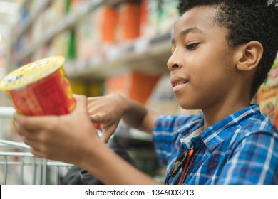 Young Afro American Kid Reading Chips Label On A Supermarket Mall	