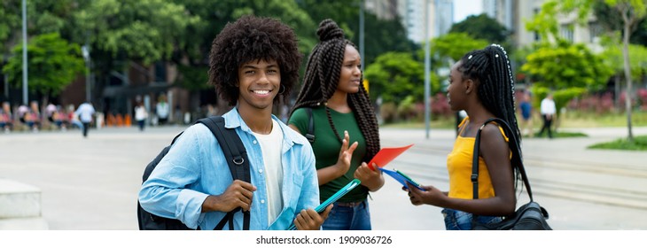 Young Afro American Male Student With Group Of Young Adults Outdoor In City In Summer