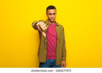 Young afro american man on yellow background showing thumb down sign with negative expression - Shutterstock ID 1304277475