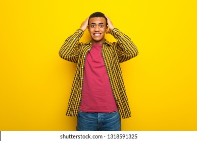 Young afro american man on yellow background takes hands on head because has migraine - Shutterstock ID 1318591325