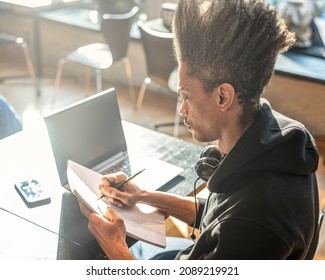 Young Afro American Man Studying With Laptop, Taking Notes On Notebook, Young Latin American Prepares For A University Exam Using Modern Technological Connections, Lifestyle Concept Copy Space