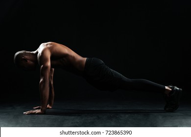 Young afro american sports man with beautiful muscular body doing pushup exercise on floor, on black background - Powered by Shutterstock