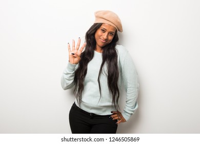 Young afro american woman on white wall happy and counting four with fingers