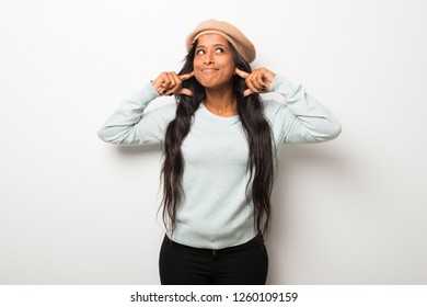 Young afro american woman on white wall covering ears with hands