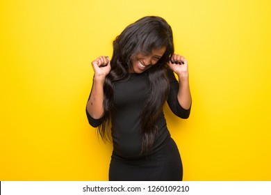 Young afro american woman on vibrant yellow background happy and jumping