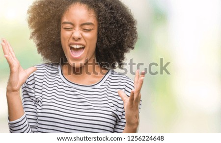 Young afro american woman over isolated background celebrating mad and crazy for success with arms raised and closed eyes screaming excited. Winner concept
