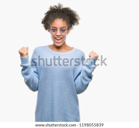 Young afro american woman wearing glasses over isolated background celebrating surprised and amazed for success with arms raised and open eyes. Winner concept.