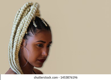 Young afro with blonde Box braids. Stylish young woman with serious expression looking down.. Copy Space.