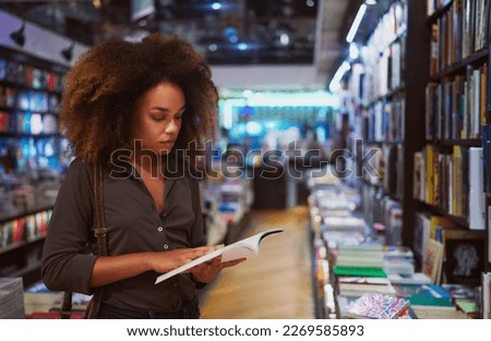 young afro brazilian woman standing holding looking reading a book in a bookstore in Ipanema
