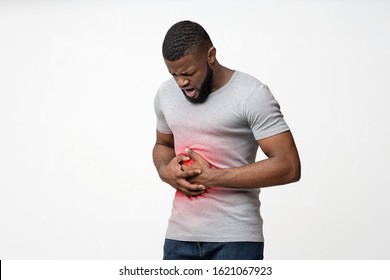 Young Afro Guy Suffering From Stomach Ulcer, Touching His Tummy Over White Background, Copy Space