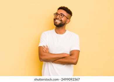 young afro man feeling happy, proud and hopeful, wondering or thinking, looking up to copy space with crossed arms - Powered by Shutterstock