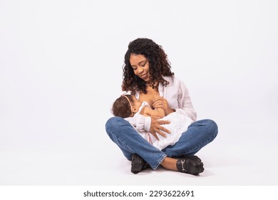 Young afro woman breastfeeding her daughter on white background