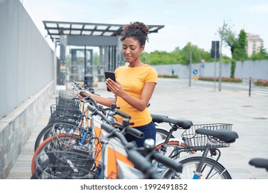 Young Afro Woman Renting Bicycle In Bike Sharing City Service