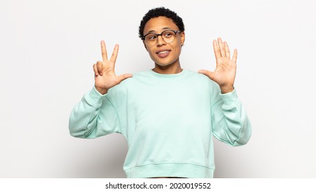 Young Afro Woman Smiling And Looking Friendly, Showing Number Eight Or Eighth With Hand Forward, Counting Down