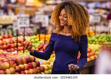 young afro woman in supermarket buying apples. - Powered by Shutterstock