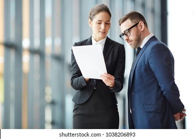 Young agent with paper explaining terms of contract to her client or business partner at meeting