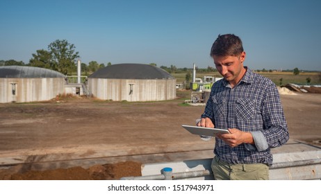 An young agronomist is using advanced technology with a tablet for controlling a quality of an organic cow manure compost used for agricultural soil cultivation and for biogas.