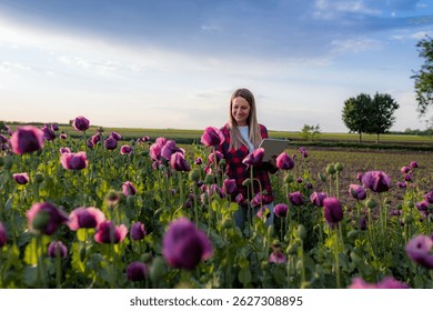 Young agronomist using a tablet while examining the growth of opium poppies in a rural field, blending agriculture with technology in a vibrant outdoor setting
