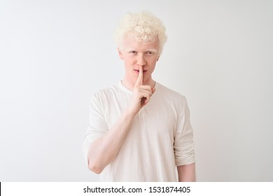 Young albino blond man wearing casual t-shirt standing over isolated white background asking to be quiet with finger on lips. Silence and secret concept. - Powered by Shutterstock