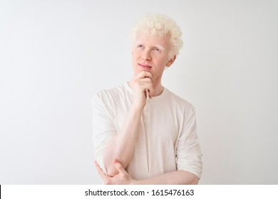 Young albino blond man wearing casual t-shirt standing over isolated white background with hand on chin thinking about question, pensive expression. Smiling with thoughtful face. Doubt concept. - Powered by Shutterstock