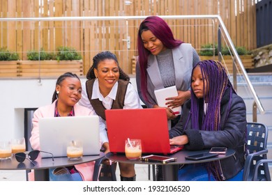 Young And Alternative Businesswomen Of Black Ethnicity. In A Teamwork Meeting, In A Cafeteria