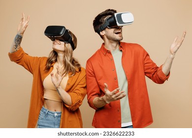Young amazed caucasian happy couple two friends family man woman wears casual clothes together watching in vr headset pc gadget isolated on pastel plain light beige color background studio portrait - Shutterstock ID 2326622233