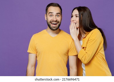 Young Amazed Couple Two Friends Family Man Woman Together In Yellow Casual Clothes Whispering Gossip And Tells Secret Behind Her Hand Sharing News Isolated On Plain Violet Background Studio Portrait