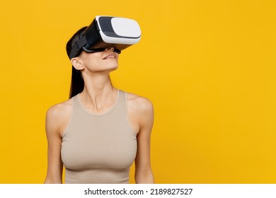 Young Amazed Gambling Happy Latin Woman 30s She Wear Casual Basic Beige Tank Shirt Watching In Vr Headset Pc Gadget Isolated On Plain Yellow Color Backround Studio Portrait. People Lifestyle Concept