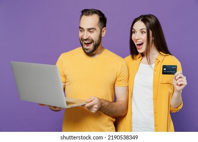 Young Amazed Happy Couple Two Friends Family Man Woman Together In Yellow Clothes Hold Laptop Pc Computer Credit Bank Card Shopping Online Order Delivery Book Tour Isolated On Plain Violet Background.